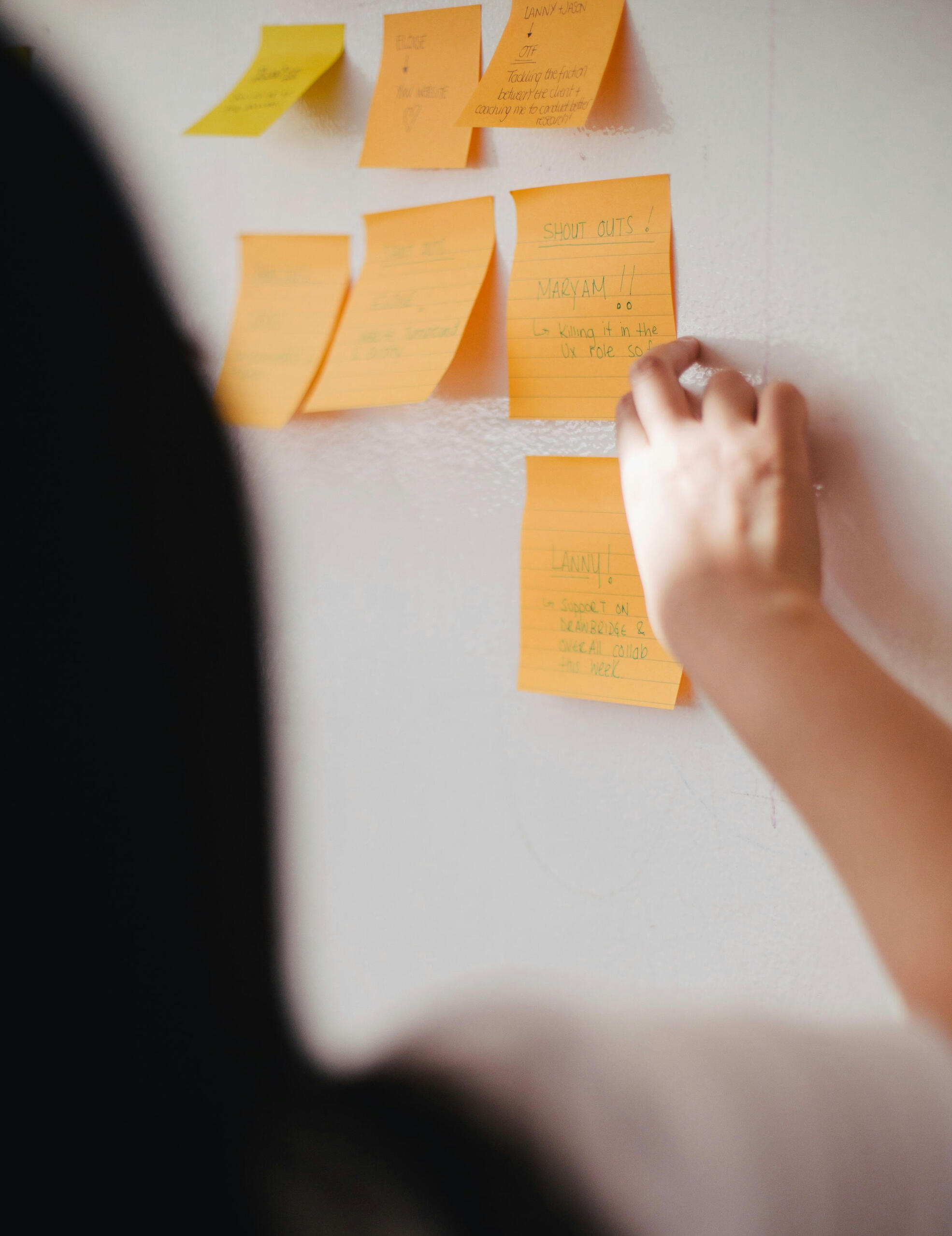 Workshop Person pointing at post-its on a board